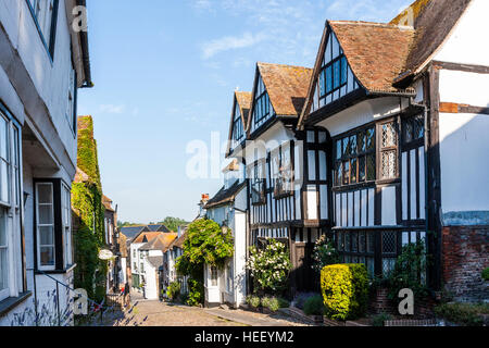 English historical town of Rye. View along cobblestone street with15th century Tudor style Hartshorn House, and other houses. Sunshine. Daytime. Stock Photo