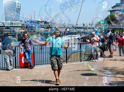 A man making a living by busking with large soapy bubbles on the Southbank in Central London, UK Stock Photo