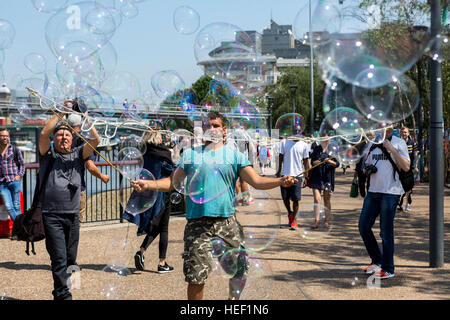 A man making a living by busking with large soapy bubbles on the Southbank in Central London, UK. Stock Photo