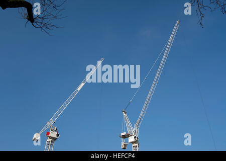 two tower cranes seen against a blue sky on a construction site in kingston upon thames, surrey, england Stock Photo