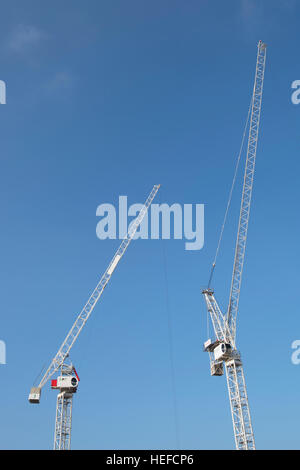 two tower cranes seen against a blue sky on a construction site in kingston upon thames, surrey, england Stock Photo