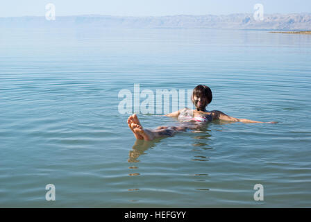 Mud covered female floats in the Dead Sea Stock Photo