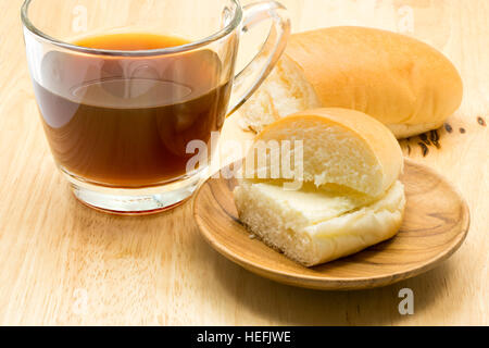 Hotdog bread filled with sweetened butter cream and a cup of coffee on wooden board Stock Photo