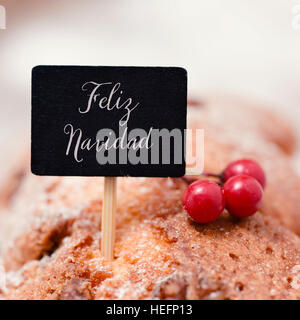 closeup of a black signboard with the text feliz navidad, merry christmas in spanish, topping a christmas cake Stock Photo