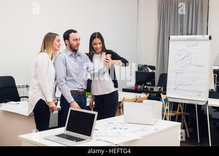 Young business people sitting in office during meeting and discussing with paperwork using laptops Stock Photo