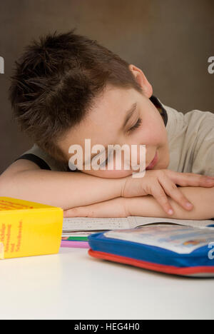 Schoolboy, boy falling asleep, sleeping while doing his homework Stock Photo