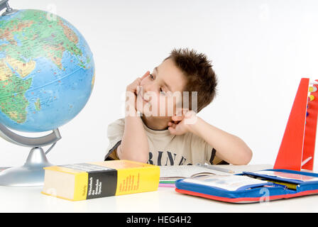 Schoolboy, seven-year-old boy doing his homework, thinking