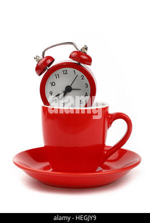 Coffee time concept, small red metal alarm clock with red bells in coffee cup or teacup with saucer, over white background, close up, low angle side v Stock Photo