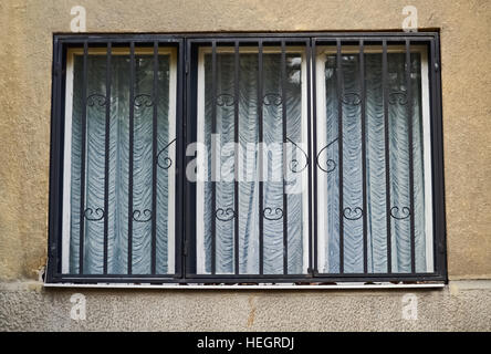 Closeup of an old window with metal bars and curtain Stock Photo
