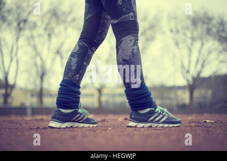 Runner legs on red running track at stadium or sports field. Stock Photo