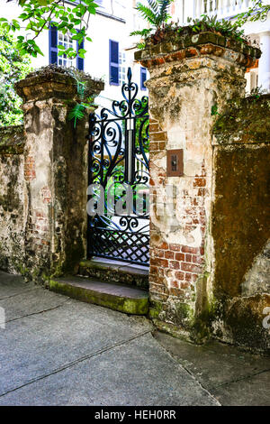 Grungy rustic authentic brick pillars support wrought iron gate entrance to Antebellum estate in historic downtown Charleston SC Stock Photo