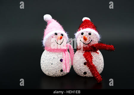 two smiling toy christmas snowman on black background Stock Photo