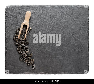 Sunflower seeds with wooden spoon on slate blackboard isolated on white background Stock Photo