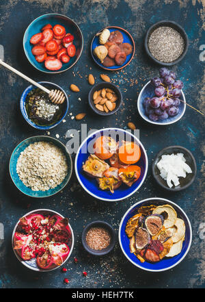 Ingredients for healthy breakfast over dark blue background, top view. Fresh and dried fruit, chia seeds, oatmeal, nuts, honey. Clean eating, vegan, v Stock Photo