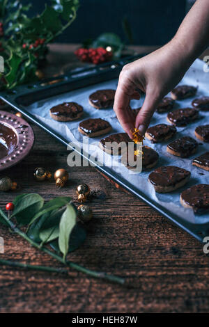 Woman putting orange zest on top of freshly baked chocolate cookies Stock Photo