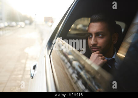 Wealthy man looking through car window while traveling in the city Stock Photo