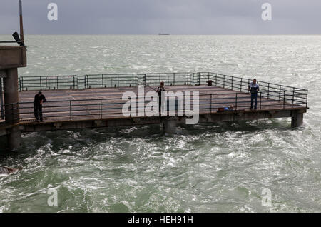 Three fisherman, on the lower deck of Deal Pier, seen at high tide. Stock Photo