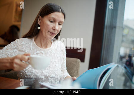 Pretty woman reading magazine and drinking tea Stock Photo