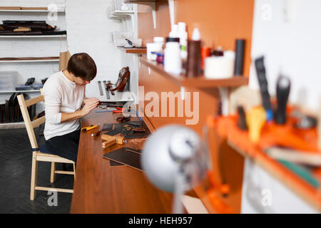Young tanner working with leather pieces in his workroom Stock Photo