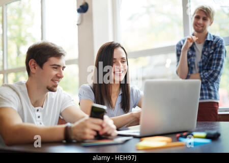 Happy groupmates searching information for carrying out home task Stock Photo