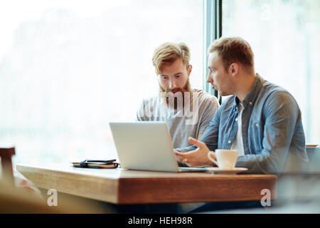 Small group of economists discussing online financial data Stock Photo
