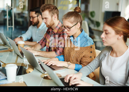Young specialists carrying out electronic task or test individually Stock Photo