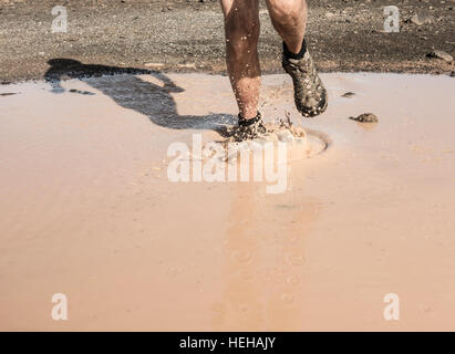 Man running through muddy puddle. Stock Photo