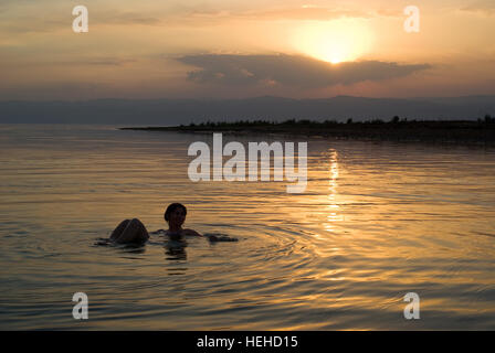 Woman floats in the Dead Sea at sunset, Jordan Stock Photo