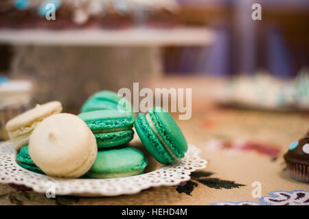 White cupcakes and green macaroons on the dish Stock Photo