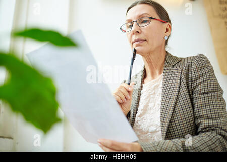 Serious teacher checking essay of student Stock Photo