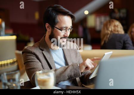 Young man siting in coffee-shop and networking Stock Photo