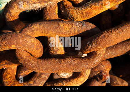 Big iron chains from an old ships anchor rusting by the harbor side close up Stock Photo