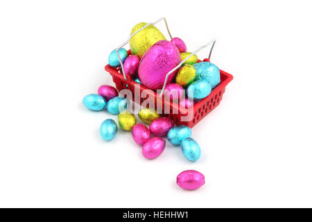 Colorful chocolate easter eggs in foil wrapping, & sitting in a shopping basket from a super market on a white background. Stock Photo