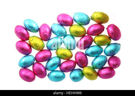 Pile of foil wrapped chocolate easter eggs in pink, blue & lime green with a white background. Stock Photo