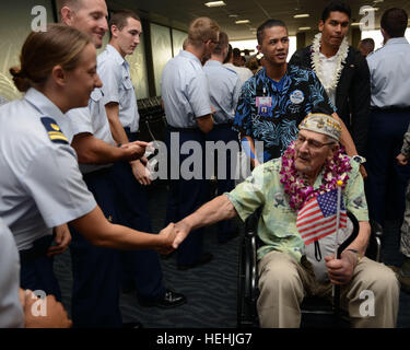 A World War II Pearl Harbor U.S. veteran is greeted by U.S. Coast Guard officers with floral leis after arriving at the Honolulu International Airport to participate in commemoration events to honoring the 75th anniversary of the Pearl Harbor attacks December 3, 2016 in Honolulu, Hawaii. Stock Photo