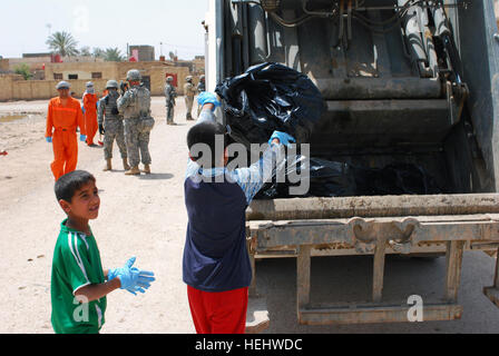 A local boy throws a trash bag into the back of a garbage truck during Dujaylah Pride Day April 18. Kids joined in the event that showed the local community the unity between the Iraqi security forces, Government of Iraq and coalition forces to strengthen community ties. Iraqi security forces lead the way for Dujaylah Pride Day 166217 Stock Photo