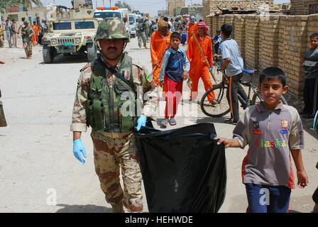 A Soldier from 3rd Battalion, 32nd Iraqi Brigade carries a trash bag with a local boy during Dujaylah Pride Day April 18. The event showed the local community the unity between the Iraqi security forces, Government of Iraq and coalition forces to strengthen community ties. Iraqi security forces lead the way for Dujaylah Pride Day 166218 Stock Photo