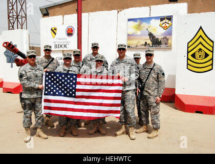 Command Sgt. Maj. Stephen J. Klunk (left) and members of Task Force Joshua, 108th Field Artillery, 56th Stryker Brigade Combat Team, display an American flag that was flown over the Base Defense Operations Center at Camp Taji, Iraq, just north of Baghdad. The flag will be sent to Susan Fryer's seventh grade writing class at Spring-Ford Middle School in Royersford, Pa., as a token of appreciation for letters sent by Fryer's group of students. Senior enlisted Soldier receives memories to last a lifetime 170778 Stock Photo