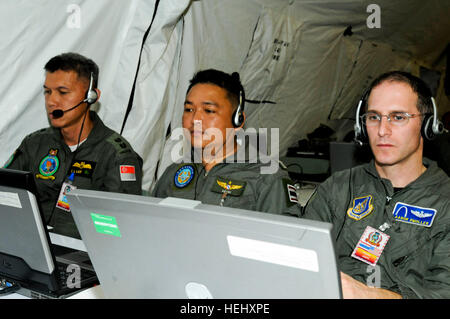 Royal Thai Air Force officers, Lt. Col. Sing Lee and Lt. Col. Kriangsak Lappaisan, along with St. Louis native, U.S. Air Force  Lt. Col. Aaron Smoller, coalition force air commander liason,157th Air Operations Group, Missouri National Guard, listen to a conference call using a distributed communications system called  Defense Connect Online at Contingency Command Post during Cobra Gold 2010. Cobra Gold is a regularly scheduled joint and multinational exercise hosted annually by the Kingdom of Thailand. This year marks the 29th anniversary for the exercise, which consists of a Global Peacekeepi Stock Photo