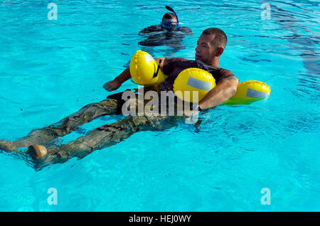 GUANTANAMO BAY, Cuba – Coast Guard Chief Petty Officer Joshua Mann of Maritime Safety and Security Team 91101 from Seattle, Wash., demonstrates a new flotation device issued to service members before training begins at the Windjammer Pool, July 23, 2009. The training was held to teach Coast Guardsmen how to use the new gear recently issued by the Coast Guard. The MSST’s mission for the next six months is to support Joint Task Force Guantanamo with water and land security. JTF Guantanamo conducts safe, humane, legal and transparent care and custody of detainees, including those convicted by mil Stock Photo