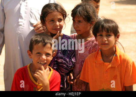 Local children wait patiently for their names to be called during a humanitarian-aid mission, supported by U.S. Soldiers assigned to Golf Battery, 82nd Field Artillery Regiment, 3rd Battalion, 2nd Brigade Combat Team, 1st Cavalry Division, in Adalla, Iraq, Aug. 9. Cavalrymen, Iraqi police go on humanitarian mission 193857 Stock Photo