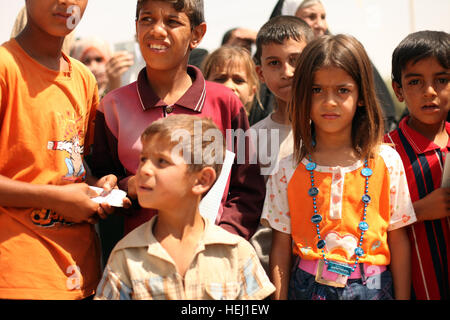 Local children wait patiently for their names to be called during a humanitarian-aid mission supported by U.S. Soldiers assigned to Golf Battery, 82nd Field Artillery Regiment, 3rd Battalion, 2nd Brigade Combat Team, 1st Cavalry Division, in Adalla, Iraq, Aug. 9. Operation Iraqi Freedom 193856 Stock Photo