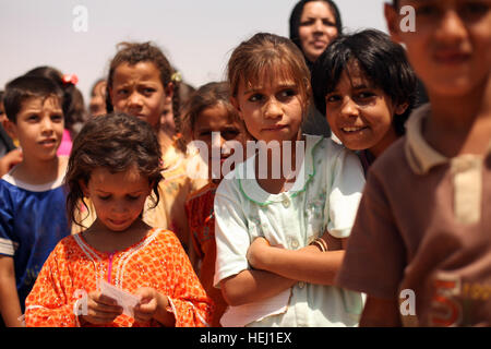 Local children wait patiently for their names to be called during a humanitarian-aid mission, supported by U.S. Soldiers assigned to Golf Battery, 82nd Field Artillery Regiment, 3rd Battalion, 2nd Brigade Combat Team, 1st Cavalry Division, in Adalla, Iraq, Aug. 9. Cavalrymen, Iraqi police go on humanitarian mission 193858 Stock Photo