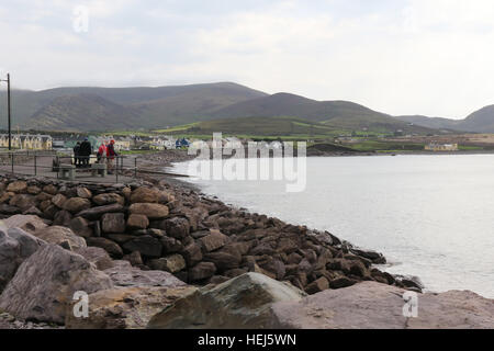 People looking out over a rocky shore at the village of Waterville on the coast of County Kerry. Ireland. Stock Photo
