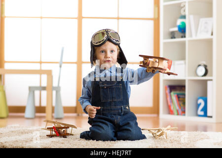 Child boy pretending to be pilot. Kid playing with toy airplanes at home. Travel and dream concept Stock Photo