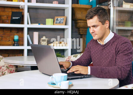 Happy young man smiling and works on his laptop Stock Photo