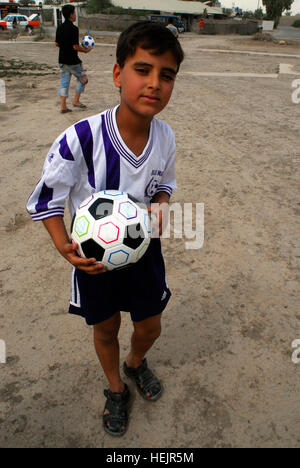 Mustafa, a young Iraqi boy from Airport village, Victory Base Complex, Iraq, holds a soccer ball May 27, after receiving them and other miscellaneous items from members of the 326th Area Support Group, Camp Victory Iraq. The clothes Mustafa is wearing are ones he received minutes before running home to change. Soccer balls and dolls; Americans make Iraqi children smile 178050 Stock Photo