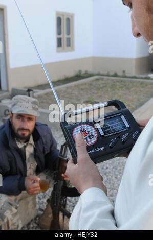 Searching for a the new Shinwar District radio station a young Afghan, with the help of an Afghan border police officer, manipulates the dial of a hand-cranked radio distributed by Afghan national and coalition security forces. The radios and new radio station are part of a media information initiative sponsored by the International Security Assistance Force's counterinsurgency program. Georgia Army National Guardsmen of 1st Squadron, 108th Cavalry Regiment, Task Force Mountain Warrior have opened two stations in the Muhmand Dara and Shinwar provinces to give the people of those regions a 'voi Stock Photo