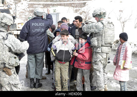 Afghan National Policeman gathers children in line a to receive goods from the U.S. military for the winter months. The goods are handed out by the 410th MP Company, out of Texas, on the road which leads to the Salang Pass near the Salang Tunnel, Parwan province, Afghanistan, Feb. 10. Operation Enduring Freedom 250326 Stock Photo