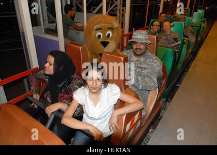 Family members of local Iraqi police officers from Kirkuk province, Iraq, ride with the Lion of Kirkuk, the Kirkuk Police mascot, and Soldiers from 2nd Brigade Combat Team, 1st Cavalry Division, during the Iraqi Police Kids Night at the Kirkuk Amusement Park, Aug. 18. Iraqi police and their families enjoy evening at Kirkuk Amusement Park 199384 Stock Photo